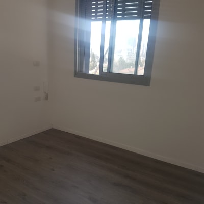 קיר לבן עם חלון ותריסים אפורים