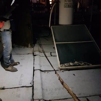 גג עם יריעות איטום וסדקים, אדם מחזיק טלפון