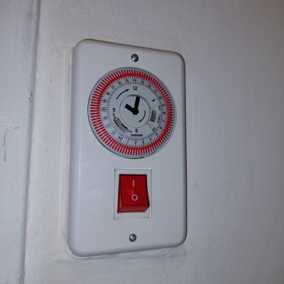 מתג חשמלי עם שעון טיימר על קיר לבן
