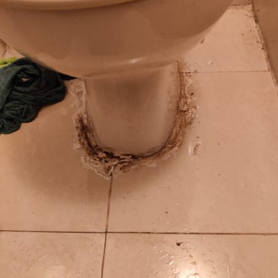 אסלה עם נזילה סביב הבסיס על רצפה רטובה