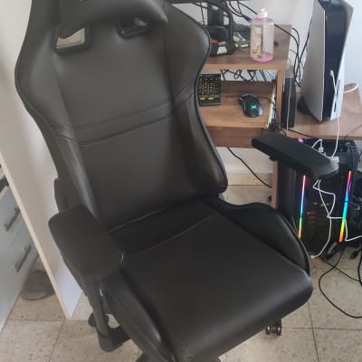 כיסא גיימינג שחור עם גלגלים ומסך מחשב