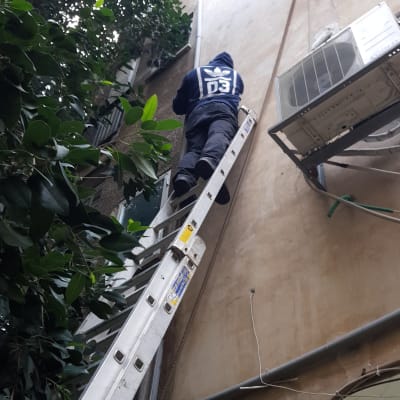 אדם על סולם ליד צינור חיצוני על קיר