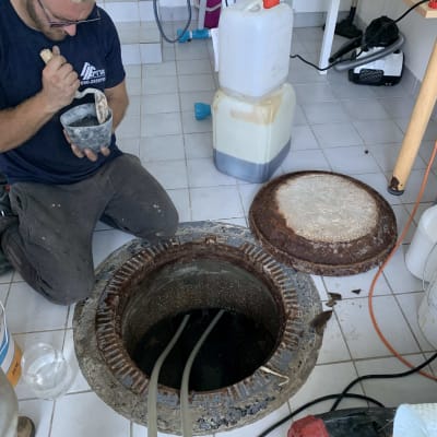 אדם עובד ליד פתח ביוב עם כלים וחומרים