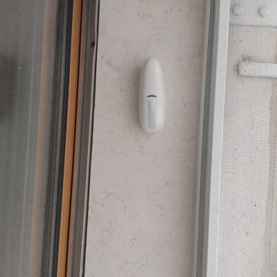 חיישן תנועה לבן מותקן על קיר ליד חלון