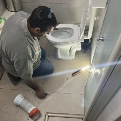 אדם עובד על תיקון אסלה עם כלי עבודה