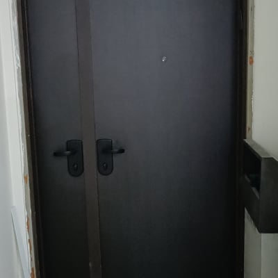 דלת כהה עם ידיות שחורות ומשקוף מתקלף