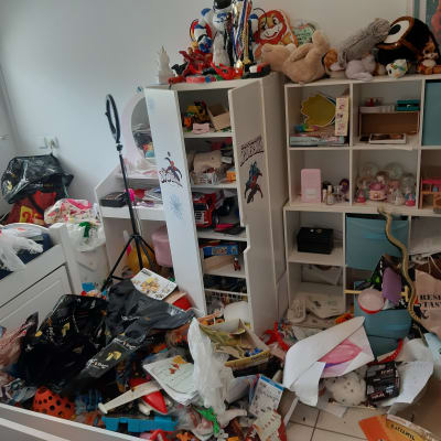 חדר מבולגן עם מדפים מלאים בצעצועים וחפצים שונים