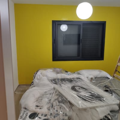 קיר צבוע בצהוב עם חלון ומנורה תלויה