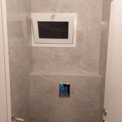 חדר שירותים עם קיר שיש, חלון קטן ואסלה