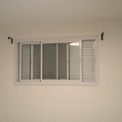חלון עם תריסים לבנים על קיר לבן