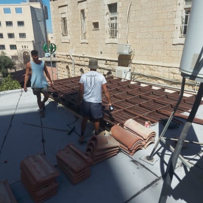 שני אנשים עובדים על גג עם ערימות רעפים