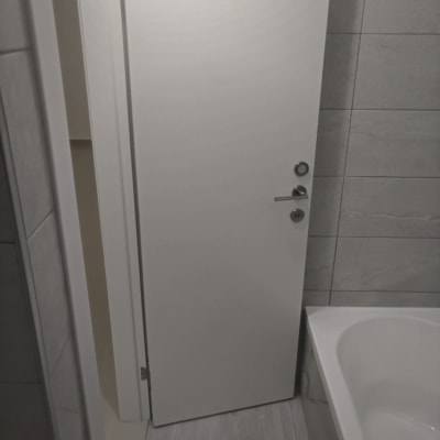 דלת לבנה חדשה עם ידית מתכת בחדר אמבטיה