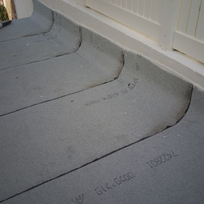 משטח איטום אפור עם כיתוב שחור ליד גדר לבנה