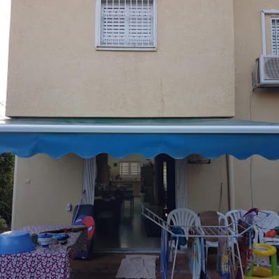סוכך כחול מותקן מעל מרפסת עם רהיטים
