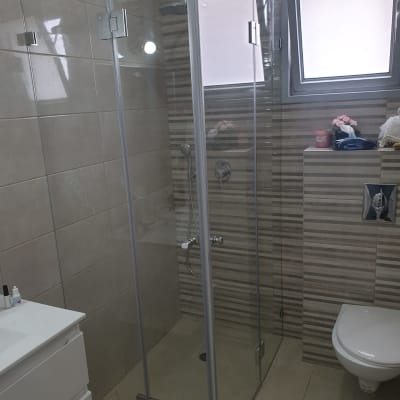 מקלחון זכוכית עם ראש מקלחת וקירות אריחים