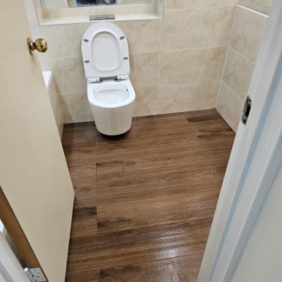 שירותים עם רצפת עץ חדשה וקירות מחופים באריחים