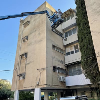 שני אנשים על מנוף עובדים על גג בניין