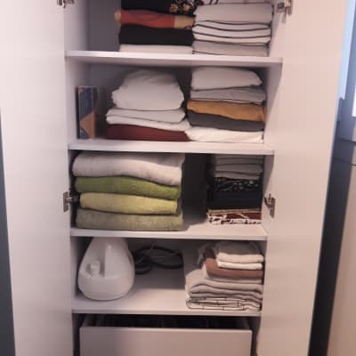 ארון עם מגבות מקופלות ומכשיר אדים על מדף תחתון