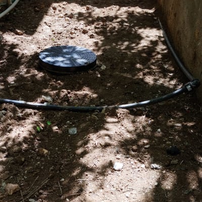 צינור פלסטיק מכוסה אדמה ליד מכסה ביוב