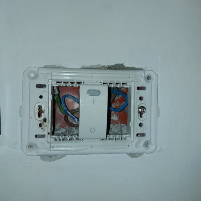 חוטי חשמל צבעוניים בתוך קופסת חשמל בקיר