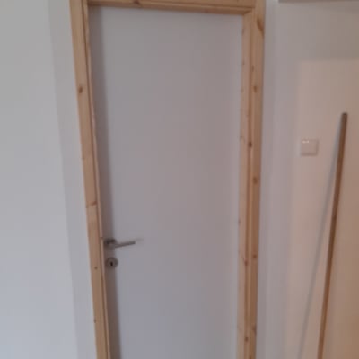 דלת עץ עם משקוף על קיר גבס לבן