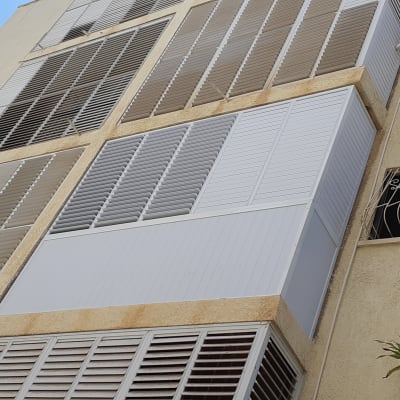 תריסי אלומיניום לבנים על קיר חיצוני של בניין