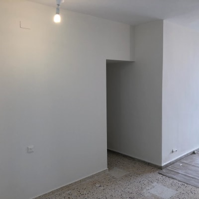 קיר צבוע בלבן עם נורה תלויה ותקרה חלקה