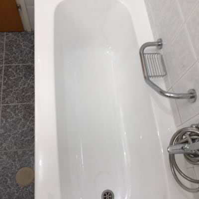 אמבטיה לבנה עם ידית מתכת ומקלחת יד