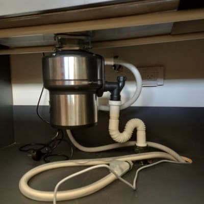 מכשיר טוחן אשפה מתחת לכיור עם צינורות חיבור