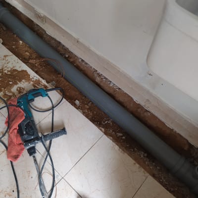 צינור אפור, מקדחה ומברג על רצפה