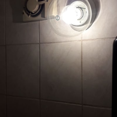 מנורה דולקת ומאוורר על קיר אריחים