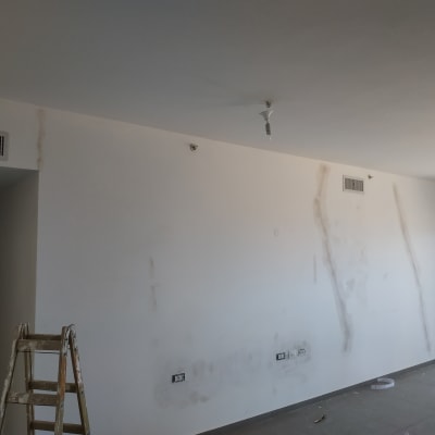 קיר עם סימני תיקון, סולם עץ, נורות חשופות