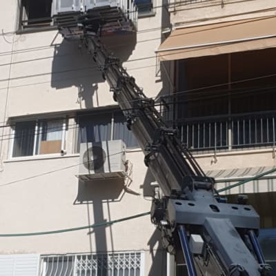 אנשים על מנוף מתקנים תריסים בחלון בניין