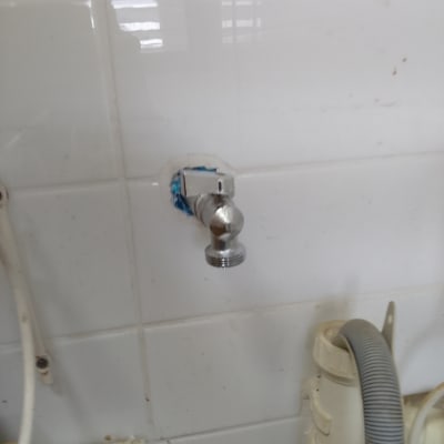 ברז מתכת מותקן על קיר אריחים לבנים