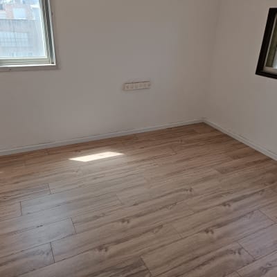 רצפת פרקט עץ בהירה בחדר ריק עם חלונות
