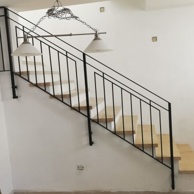 מעקה מתכת שחור על מדרגות עץ בהירות