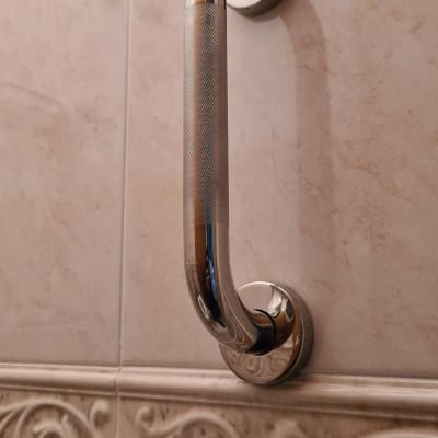 ידית אחיזה מתכתית על קיר אריחים בחדר אמבטיה