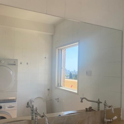 מראה גדולה על קיר לבן בחדר אמבטיה