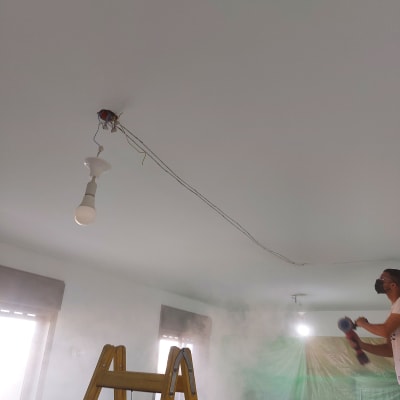 חשמלאי עובד על תקרה עם חוטי חשמל חשופים