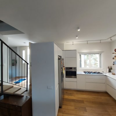 מטבח מודרני עם ארונות לבנים ורצפת עץ