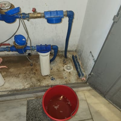 דליפה בצנרת עם דלי אדום לאיסוף מים