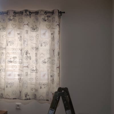 סולם מתקפל ליד חלון עם וילון מעוטר