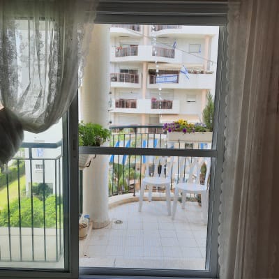 חלון אלומיניום עם וילון לבן ומרפסת