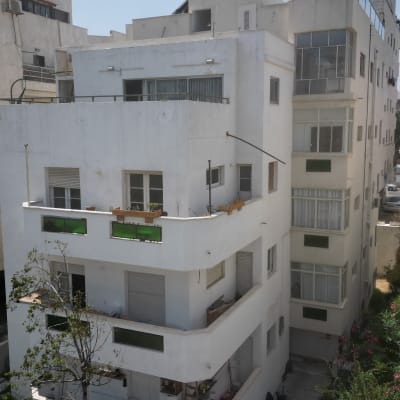 בניין מגורים לבן עם מרפסות וחלונות