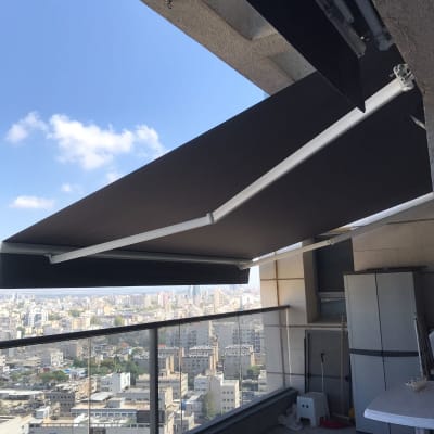 סוכך שחור נפתח במרפסת עם נוף עירוני