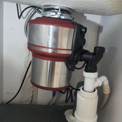 מכשיר טוחן אשפה מתחת לכיור עם צינורות חיבור