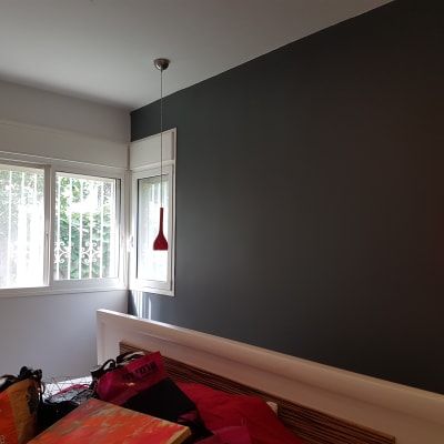 קיר צבוע בצבע כהה עם מנורה אדומה תלויה