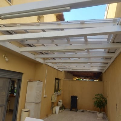 פרגולה מעץ לבן בחצר עם צמחים ועציצים