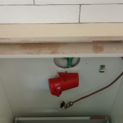 שקע חשמלי אדום וצינור נחושת בארון חשמל