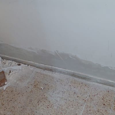 קיר צבוע חלקית עם סימני טיח על הרצפה